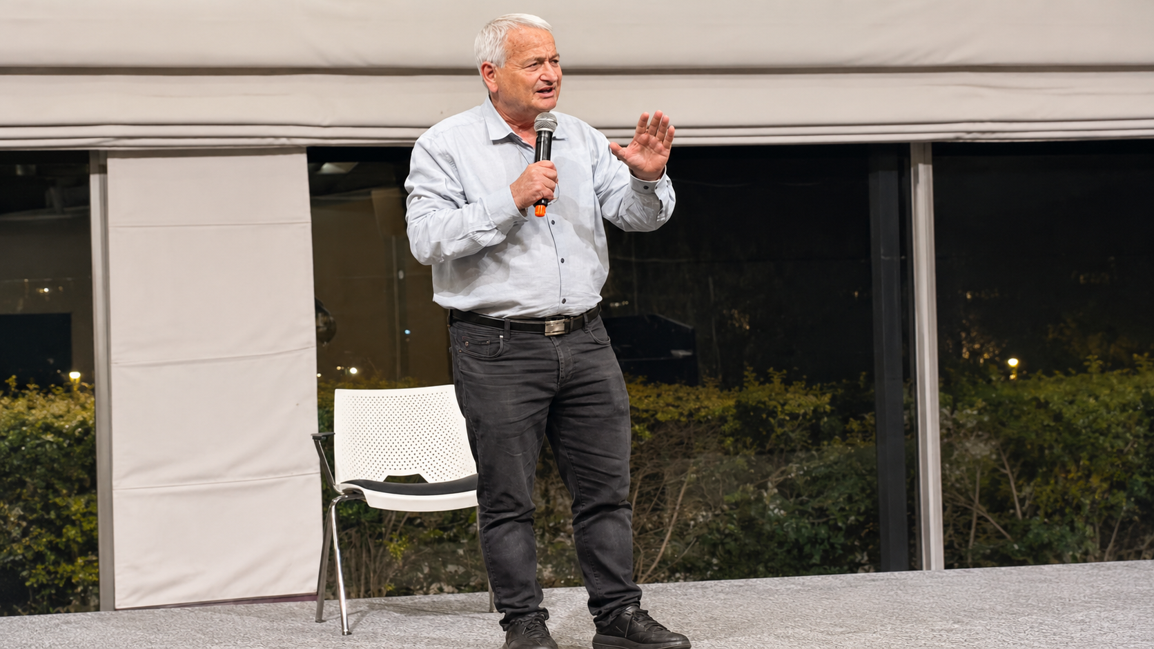 Older Speaker Gesturing on Stage